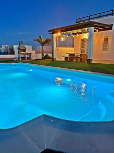 a large blue swimming pool in front of a house at MILÚ GOLF LUXURY HOUSE in Caleta De Fuste