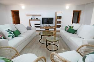 a living room with white couches and a tv at MILÚ GOLF LUXURY HOUSE in Caleta De Fuste