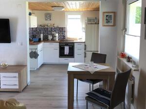 Bungalow Rudensicht في Freest: مطبخ مع طاولة ومطبخ مع دواليب بيضاء