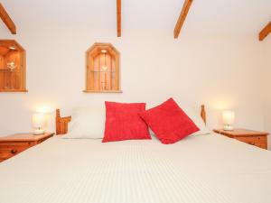 Schlafzimmer mit einem weißen Bett und roten Kissen in der Unterkunft The Hideaway in St Austell