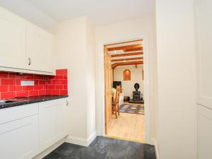 eine Küche mit weißen Schränken und einer roten Kachelwand in der Unterkunft The Hideaway in St Austell