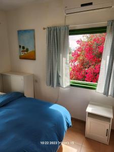 a bedroom with a blue bed and a window at Tal Shahar room in Tal Shaẖar