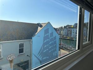 a window with a view of a river and buildings at Weymouth Harbour Luxury Apartment in Weymouth