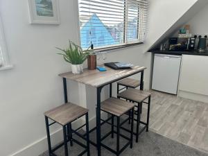 a kitchen with a table and two stools at Weymouth Harbour Luxury Apartment in Weymouth