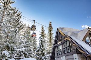einen Skilift über ein Haus mit schneebedeckten Bäumen in der Unterkunft Pinnacle Ridge 23 - Ski In Ski Out, Newly Renovated, Private Hot Tub, Gas Fireplace in Whistler