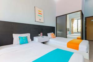 バニュワンギにあるSans Hotel Borobudur Banyuwangiのベッドルーム1室(ベッド2台、鏡付)