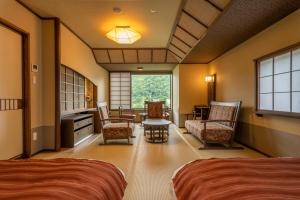 a bedroom with two beds and a table and chairs at Jozankei Onsen Yurakusoan in Jozankei
