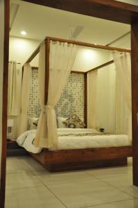 sypialnia z łóżkiem z baldachimem i zasłonami w obiekcie Hotel Kalyan's - Mansingh Inn w mieście Khambhāliya