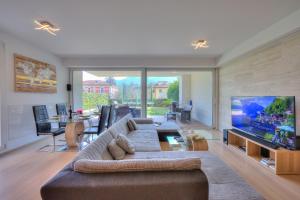 uma sala de estar com um sofá e uma televisão de ecrã plano em Rebecca Garden - Happy Rentals em Lugano