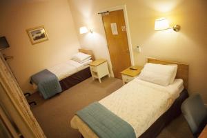 a hotel room with two beds and a table at The Derg Arms B&B in Castlederg