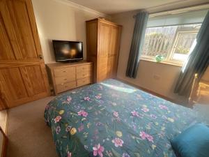 a bedroom with a bed and a television and a dresser at Sunnyside in Veryan