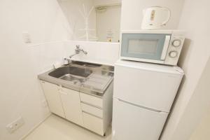 eine kleine Küche mit einer Mikrowelle auf dem Kühlschrank in der Unterkunft プロスパービル3b in Kume