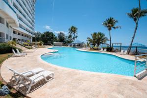 een zwembad in een resort met stoelen en de oceaan bij Escape To Paradise Beachfront 2br beach in La Puntica de Juan Dolio