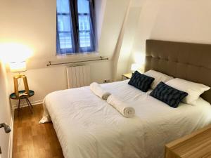 een slaapkamer met een groot wit bed met 2 kussens bij La Tour de Jeanne : Hypercentre charme et design in Rouen