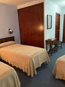 a hotel room with two beds and a desk at Hotel Folch in Sant Julià de Lòria