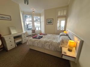 a bedroom with a bed and a desk and windows at Lower Tresulian in Saint Mawes