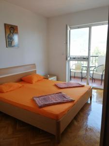 um quarto com uma cama com lençóis cor-de-laranja e uma grande janela. em Stan u centru Bara em Bar