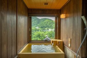 Jozankei的住宿－Jozankei Onsen Yurakusoan，窗户客房内的浴缸