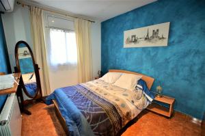 1 dormitorio con cama y pared azul en Villa Olombel, en Maçanet de la Selva