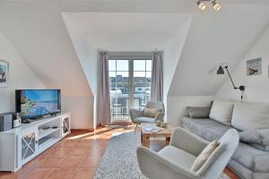 ein Wohnzimmer mit einem Sofa und einem TV in der Unterkunft Haus am Falkenweg Haus am Falkenweg Appartement 6 in Scharbeutz