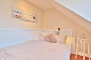 1 Schlafzimmer mit einem weißen Bett mit einem weißen Kopfteil in der Unterkunft Haus am Falkenweg Haus am Falkenweg Appartement 6 in Scharbeutz