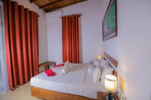 a bedroom with a white bed with red curtains at Sigiri Asna Nature Resort in Sigiriya