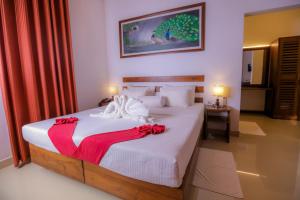 Un dormitorio con una gran cama blanca con arcos rojos. en Sigiri Asna Nature Resort en Sigiriya