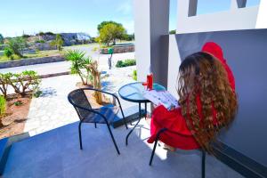 a woman sitting at a table on a balcony at Elafonisi Paradise with Parking, WiFi, - Walking Distance to the Beach in Elafonisi