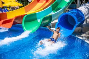 a young boy on a water slide at a water park at Prestige Deluxe Hotel Aquapark Club - All inclusive in Golden Sands