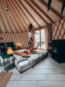 Una donna che salta su un letto in una yurta di Hoya Glamping a Gostynin