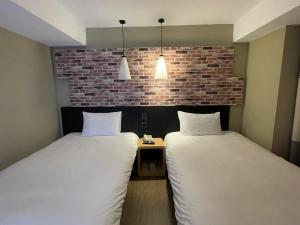 2 camas en una habitación con una pared de ladrillo en 苓旅中山館-Lininn ZhongShan en Taipéi