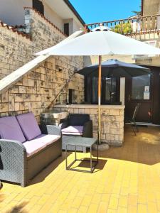 a patio with a couch and an umbrella at Apartments Vila Toni in Portorož