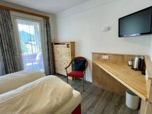 a room with two beds and a desk with a television at Pension Bavaria in Mittenwald