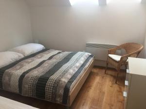 a bedroom with a bed and a chair at Vinařský apartmán Simenon in Chvalovice