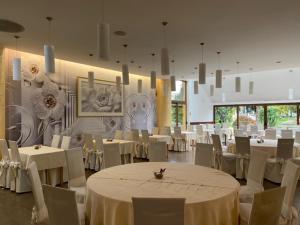 un salón de banquetes con mesas blancas y sillas blancas en Hotel Picok, en Ðurđevac