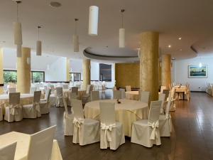 un salón de banquetes con mesas blancas y sillas blancas en Hotel Picok, en Ðurđevac