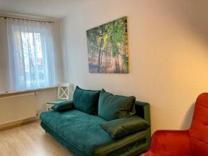 ein Wohnzimmer mit einer grünen Couch und einem Gemälde an der Wand in der Unterkunft Altes Uhrwerk in Hasselfelde