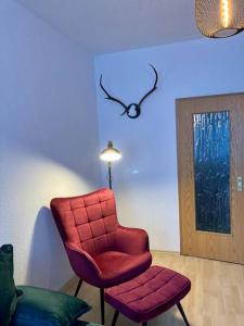 una silla roja y un taburete en una habitación en Altes Uhrwerk, en Hasselfelde
