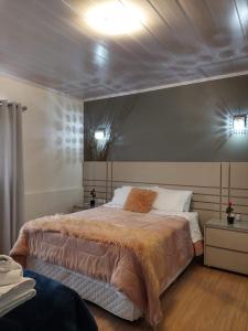 um quarto com uma cama grande e duas luzes na parede em Casa em Gramado em Gramado