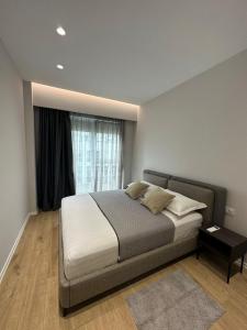 a bedroom with a bed and a large window at NEW Brilant Apartment in Tirana