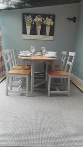 a wooden table with chairs and a table with flowers on it at Seaside, Exmouth Centre - sleeps 6+ in Exmouth