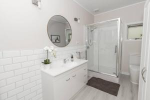 a white bathroom with a sink and a shower at Rustling Oaks NZ Boho Pool House in Cambridge