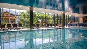 Hotel Czarny Potok Resort SPA & Conference في كرينيتسا زدروي: مسبح كبير مع كراسي في مبنى