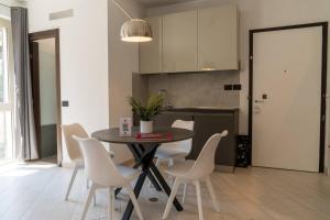 a kitchen with a table and white chairs in a room at [GALLERIA DUOMO] Luxury Design Apartment in Brescia
