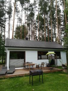 a small white cabin with a deck with a picnic table at Sisaliku Puhkemaja saunaga in Luke