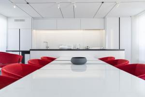 une salle de conférence avec une table blanche et des chaises rouges dans l'établissement La Source Exclusive Apartment, à Paris