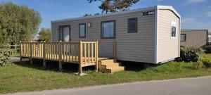a tiny house with a porch and a wooden ramp at Camping de la Plage in Marck