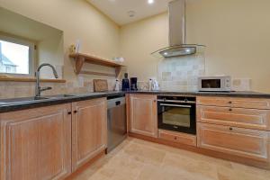 eine Küche mit Holzschränken, Spüle und Mikrowelle in der Unterkunft Petit Marigny - Belle maison pour 10 voyageurs in Alexain
