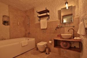 a bathroom with a tub and a toilet and a sink at The Owl Cave Hotel in Göreme