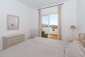 a white bedroom with a bed and a window at Penthouse with a fantastic view in La Cala de Mijas